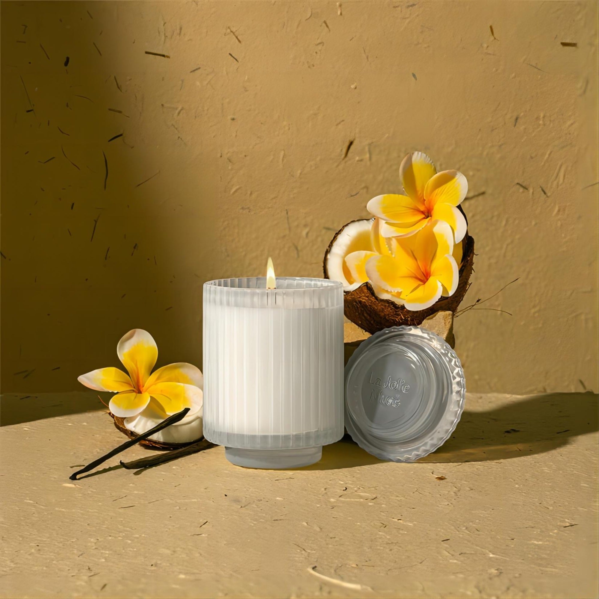 Editorial Shot of Amélie - Vanilla Coconut lit at the center of the scene surrounded by coconut shells and flowers.
