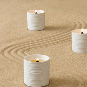 Collection shot of Lucienne candles in various scents placed on sand