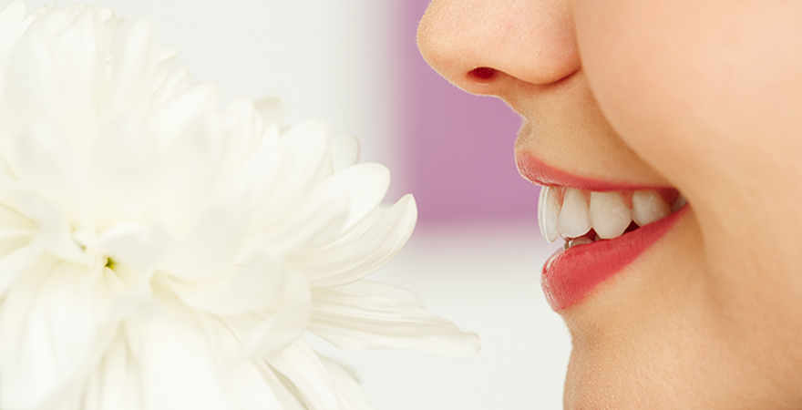 woman smiling while smelling white flower