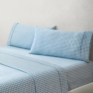 Paulina Blue Check Picot Edge 200 count cotton sheet set. White and blue gingham pillows and white and blue gingham sheets on bed from side angle.