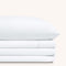 Camille Classic White bed sheet set. Single white pillow stacked on folded white sheet set.