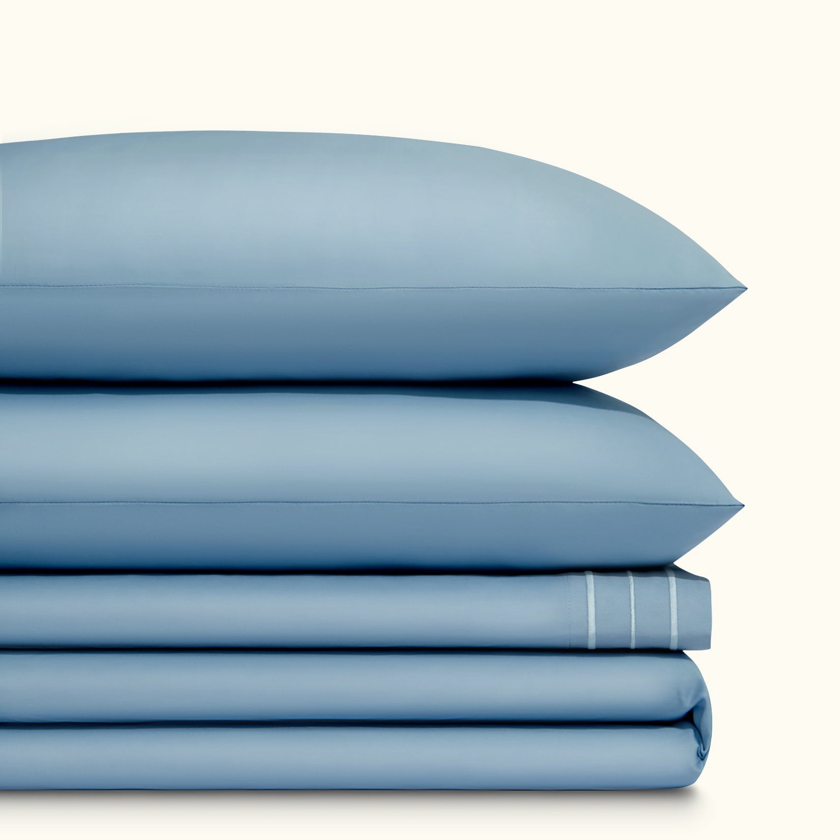 Paulina Sky Blue Satin Stitched Cuff 200 thread count cotton bed sheet set. Two sky blue pillows stacked on folded sky blue sheet set.