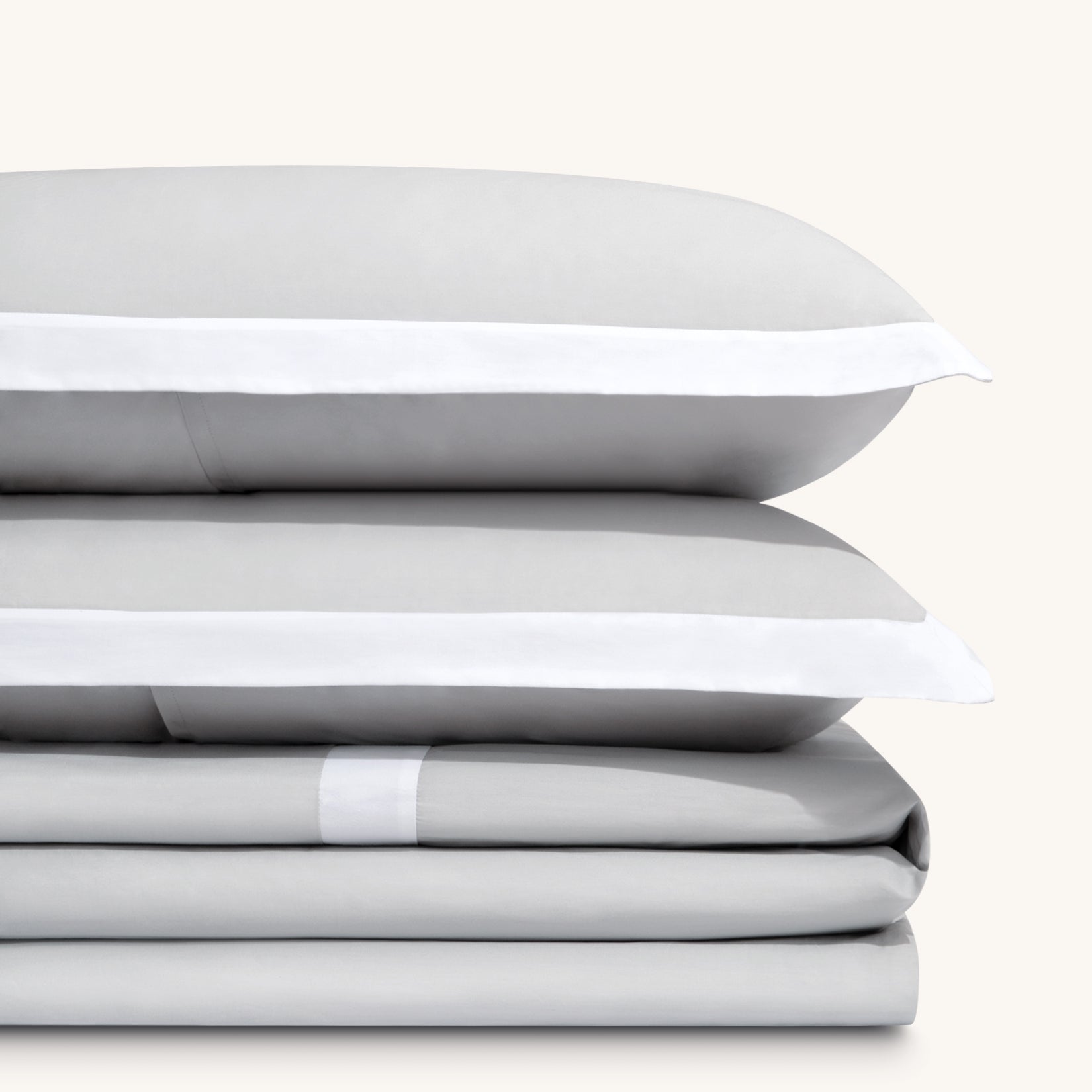 Paulina Foggy Gray 200 thread count combed cotton bed sheet set. Two white and gray pillows stacked on folded white and gray sheet set.Paulina Foggy Gray 200 thread count combed cotton duvet set. Two white and gray pillows stacked on folded white and gray duvet set.