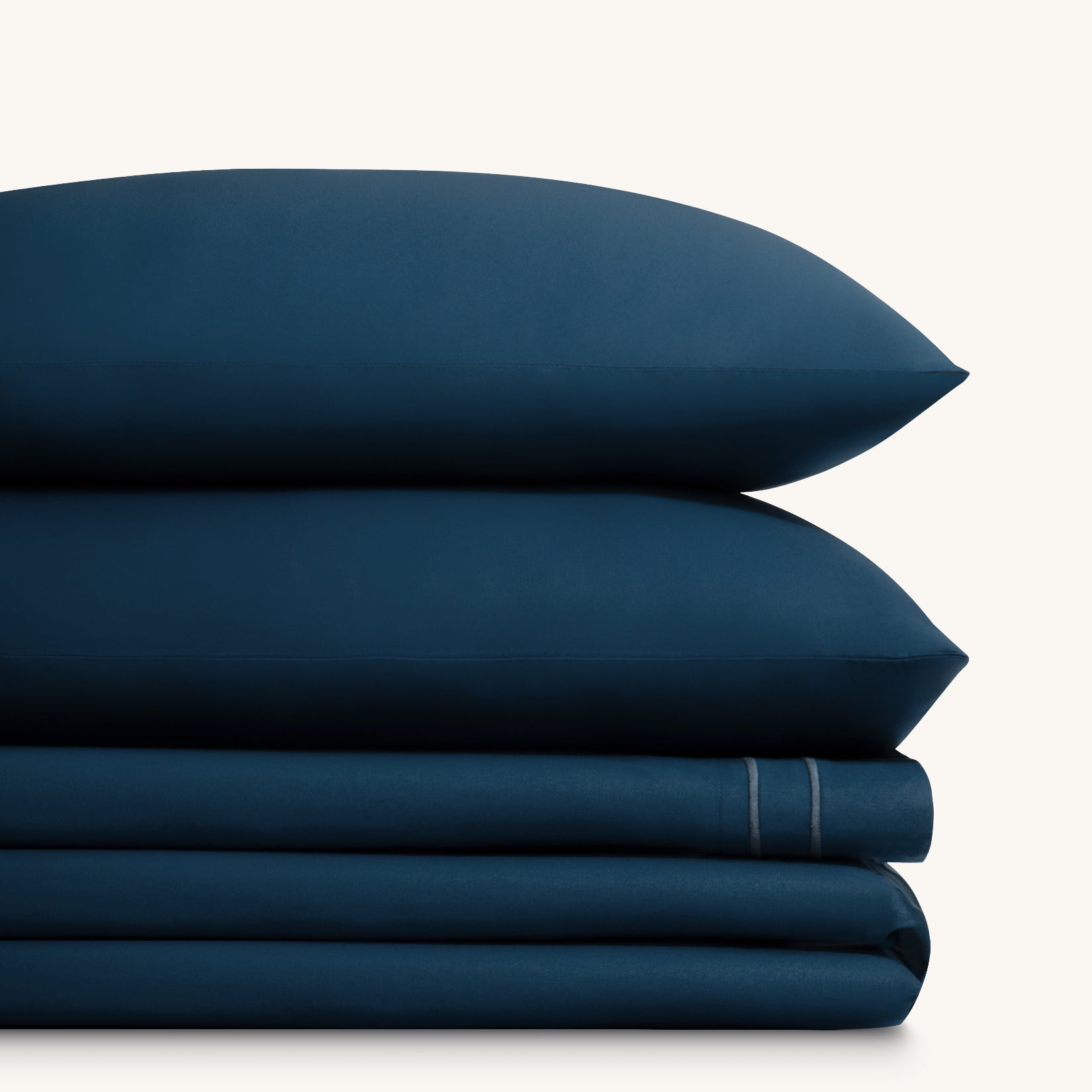 Sofia Navy Blue Double Satin Stitched Cuff 300 thread count cotton bed sheet set. Two navy pillows stacked on folded white sheet set.