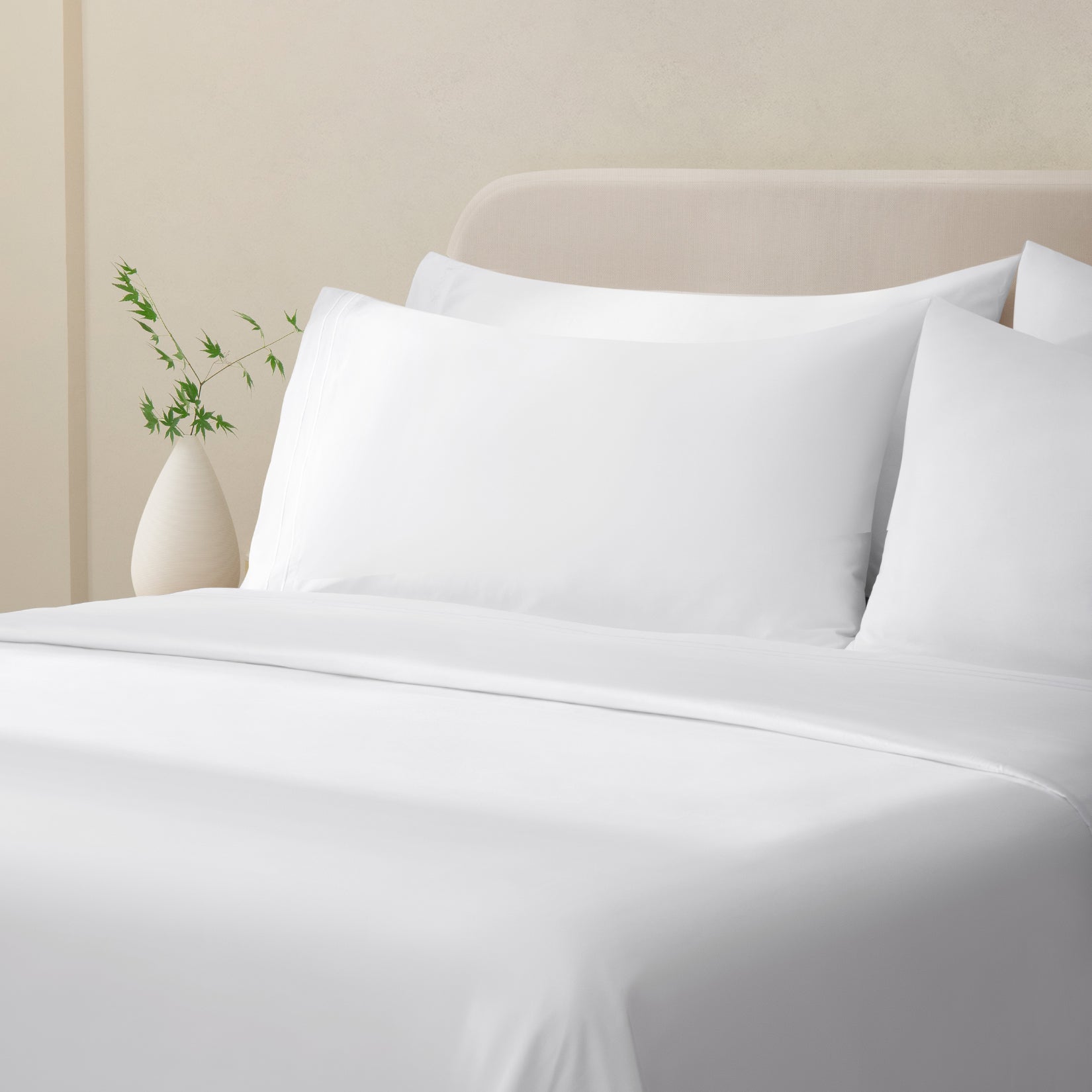 Sofia Classic White Double Satin Stitched Cuff 300 thread count cotton bed sheet set. White pillows and white cotton sheets on bed next to side table and plant.