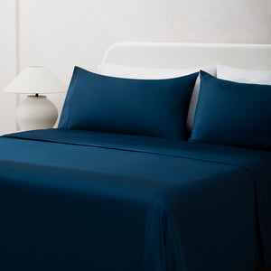 Sofia Navy Blue Double Satin Stitched Cuff 300 thread count cotton bed sheet set. Navy pillows and navy cotton sheets on bed next to side table and lamp.