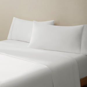Olivia soft white linen bed set. Soft white linen pillows and soft white linen sheets on bed from side angle.