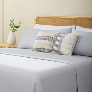 Olivia foggy gray linen sheet set. Foggy gray linen pillows and foggy gray duvet on bed with plant on side table from side angle.