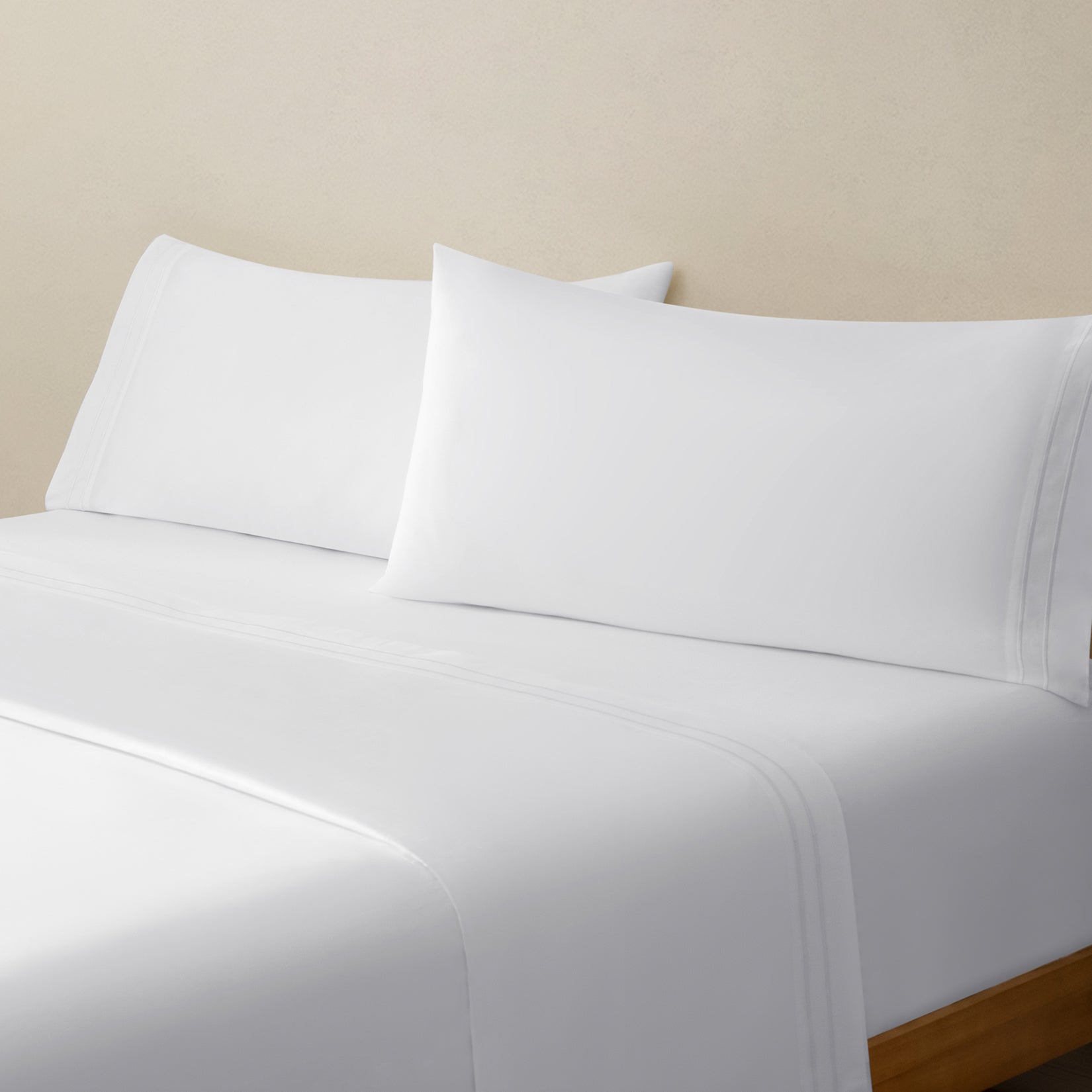 Sofia Classic White Double Satin Stitched Cuff 300 thread count cotton bed sheet set. White pillows and white cotton sheets on bed from side angle.