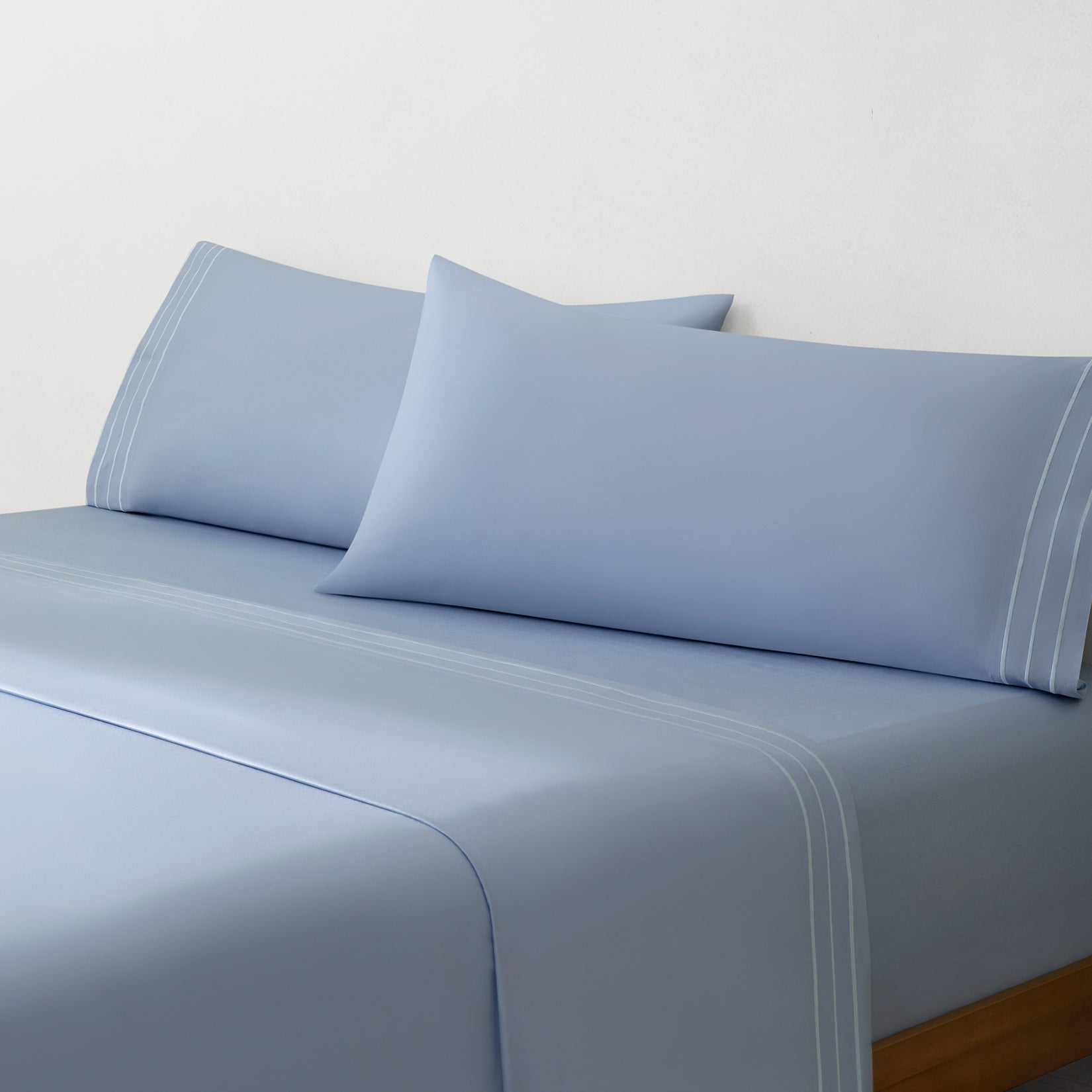 Paulina Sky Blue Satin Stitched Cuff 200 thread count cotton bed sheet set. Sky blue pillows and sky blue cotton sheets on bed.