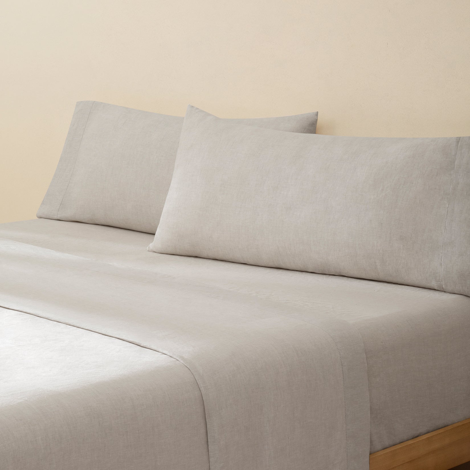 Olivia natural taupe linen bed set. Natural taupe linen pillows and natural taupe linen sheets on bed from side angle.