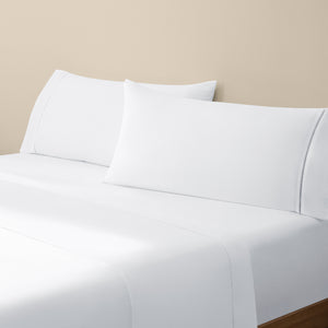 Camille Classic White bed set. White pillows and white sheets on bed from side angle.