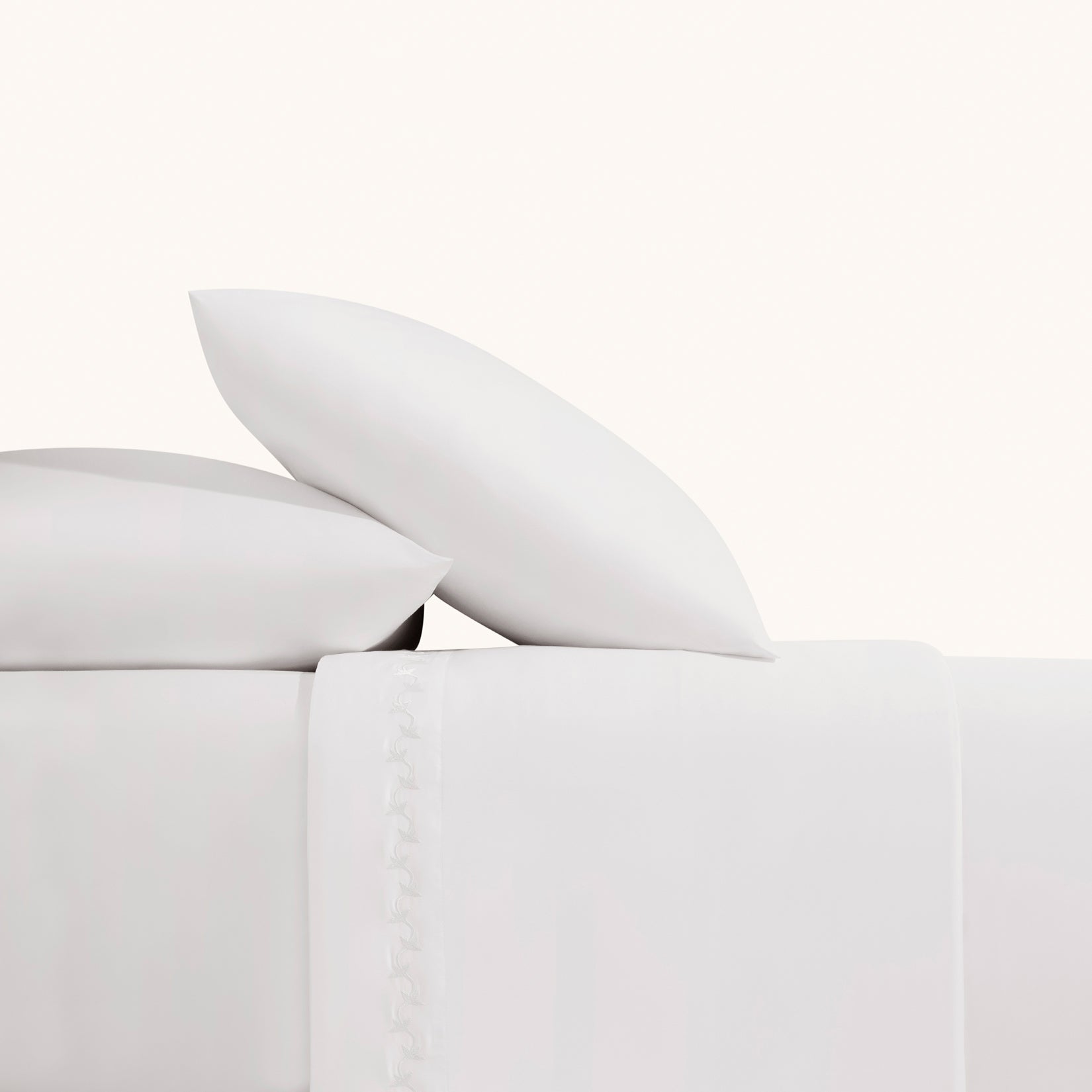 Nina Classic White 600 thread count sheet set. White embroidered pillows and white embroidered sheets with on bed from side view.