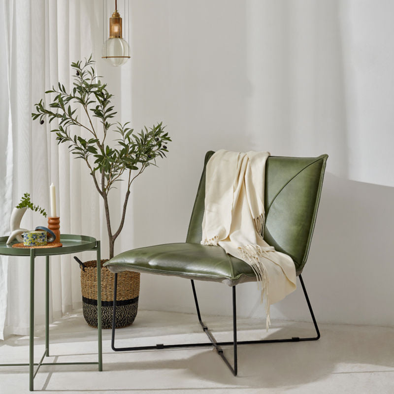 The creamy white throw is displayed on a green chair, next to a coffee table and a small tree plant.