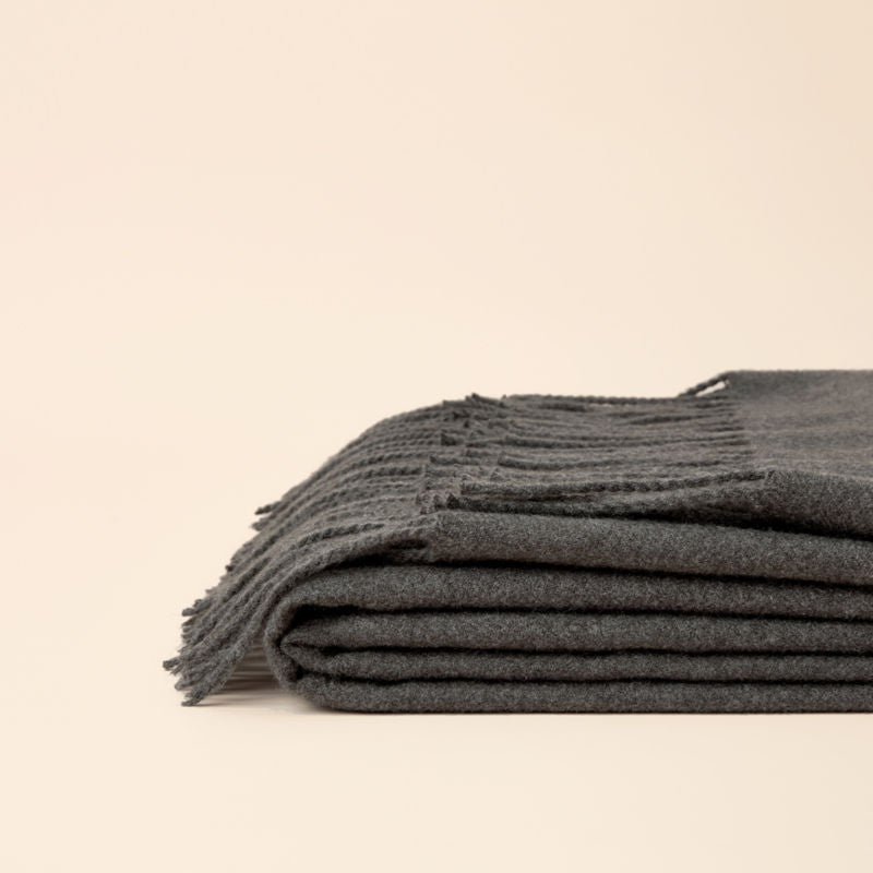 A full view of a folded Angie smoky gray faux fleece fringed throw blanket is displayed.