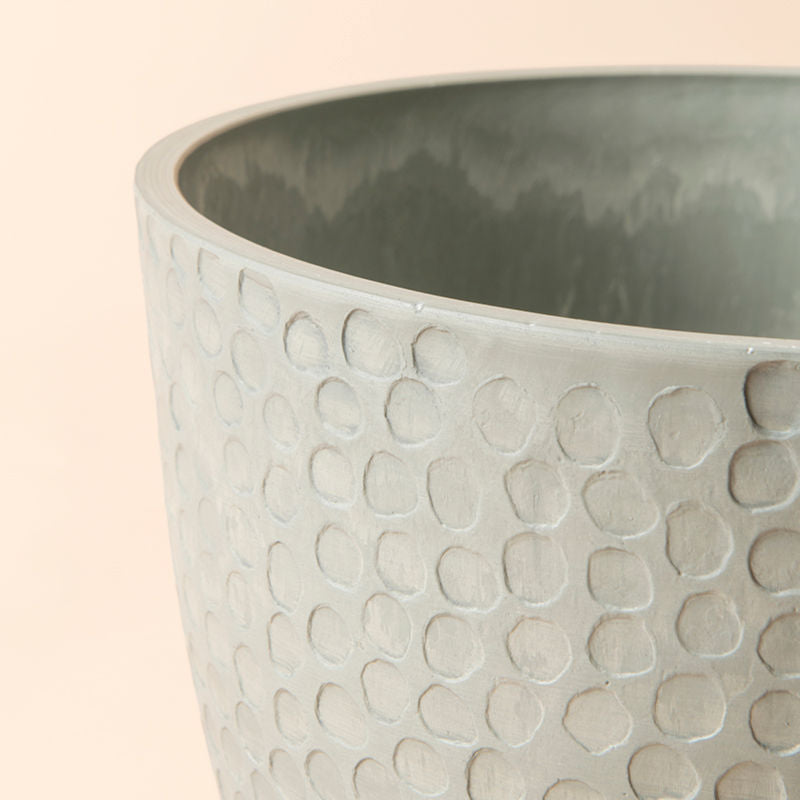 A close up of a large plastic planter,  with its exterior filled with honeycomb pattern and  interior with natural texture.