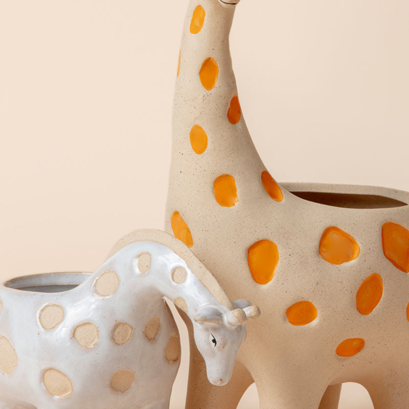 A close up of giraffe planter pots, showing its sandy gravel surface with a glossy ceramic pattern.