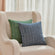 Two pillows in the euro sham herringbone weave pillow cover is displayed on a beige sofa. One is blue, the other is green.