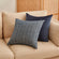 A pair of pillows in blue euro sham herringbone weave pillow cover is displayed on a beige couch showing its front and back sides.
