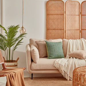 A group of pillows is displayed on a sofa in the lounge across from a brown three-leaf screen.