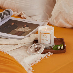 A burning candle and a book on a piece of orange fabric.