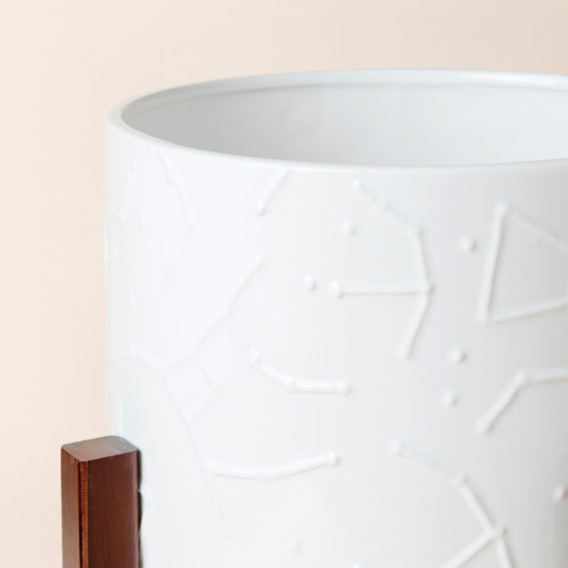 A close up of white ceramic pot with cosmos pattern, showing the elaborate star chart embossings on its exterior.