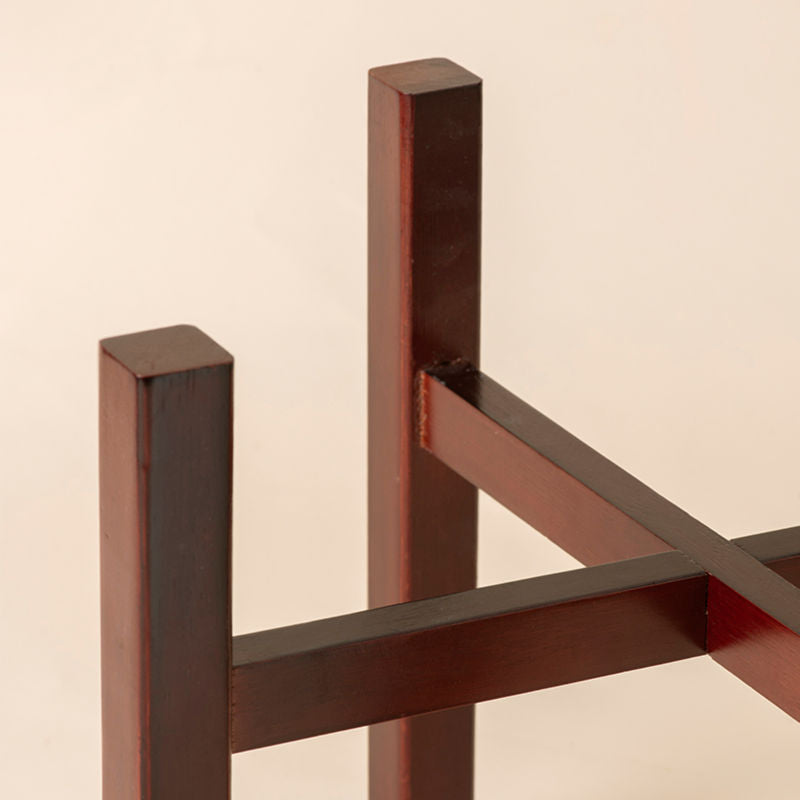 A close up of dark wooden stand of cosmos planter, structured by two crossing pieces to achieve stability.