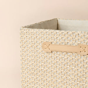 A close-up of cotton rope storage cube, showing neutral lace decorations and reinforced handles.