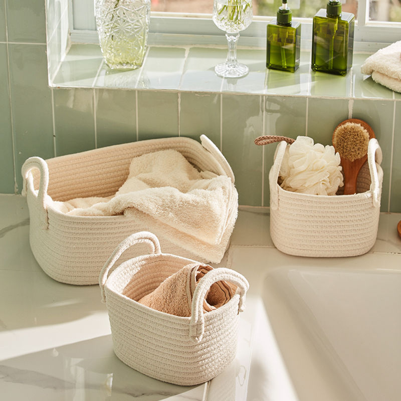Three cotton rope baskets storing a lot of bathing towels are placed next to a bathtub.