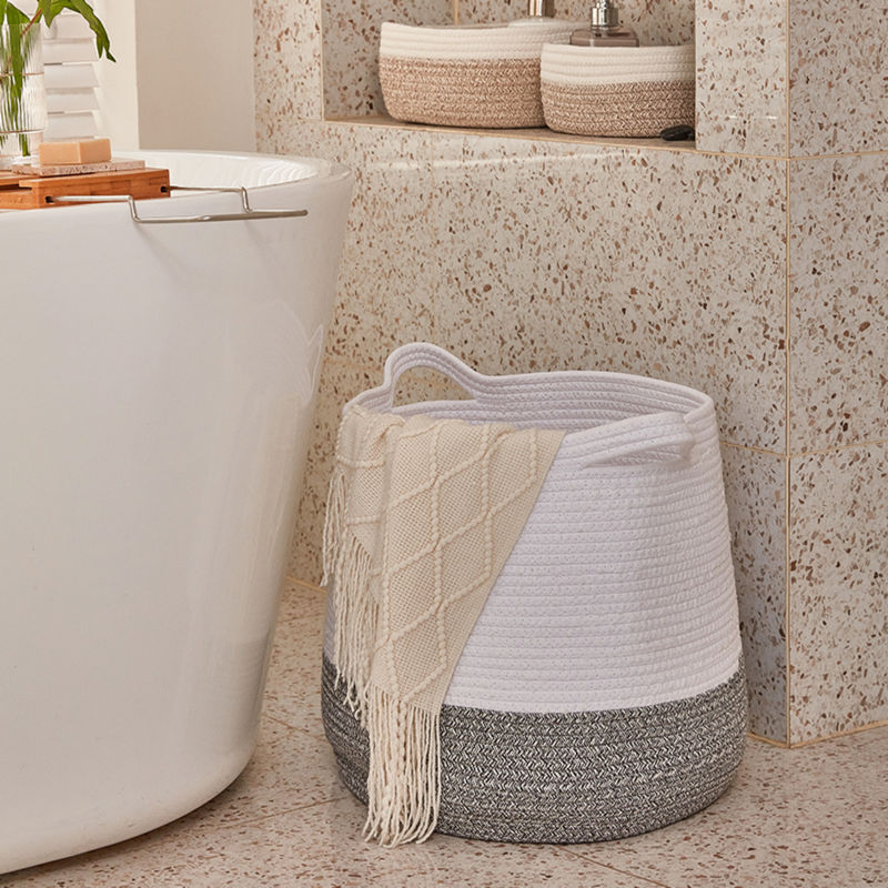 A cotton laundry basket storing a beige scarf, placed next to a white bathtub at the corner of the bathroom.