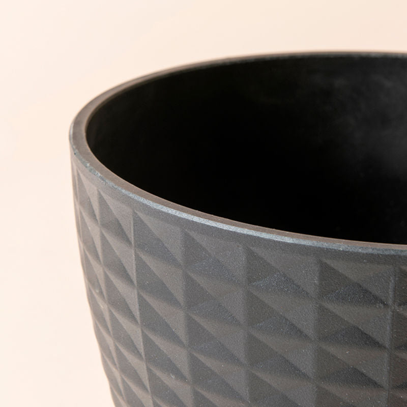 A close up of matte black planter, showing the chic geometric pattern around its exterior.