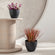 A pair of two matte black planters are displayed in a staggered way, each potted with colorful plants.