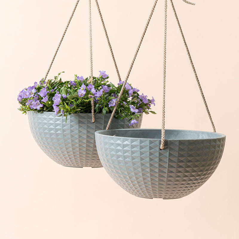 A set of two gray hanging planters with cube pattern design, one of which holds plants.