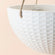 A close up of matte white hanging planter, showing its  geometric pattern and sturdy hanging rope.
