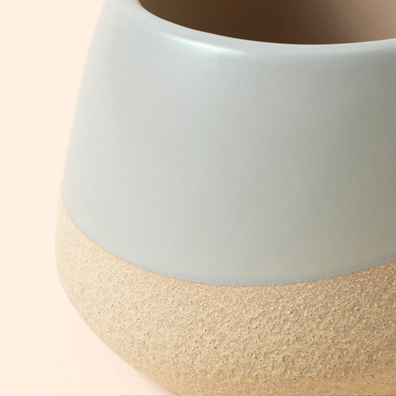 A picture of the Duna gray & beige pots in smaller size, shows a curvy edge towards the bottom.