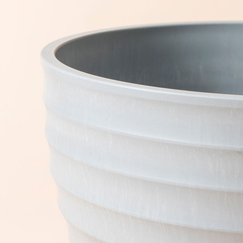 A close-up of the light gray pot, showing its smooth curves and ridges design feature.