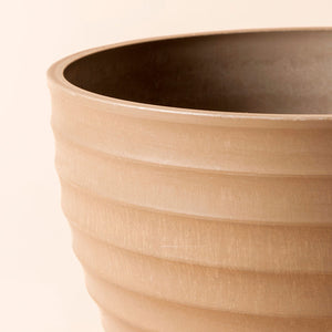 A close-up of the taupe planter, showing its horizontal ridge design and smooth curves.