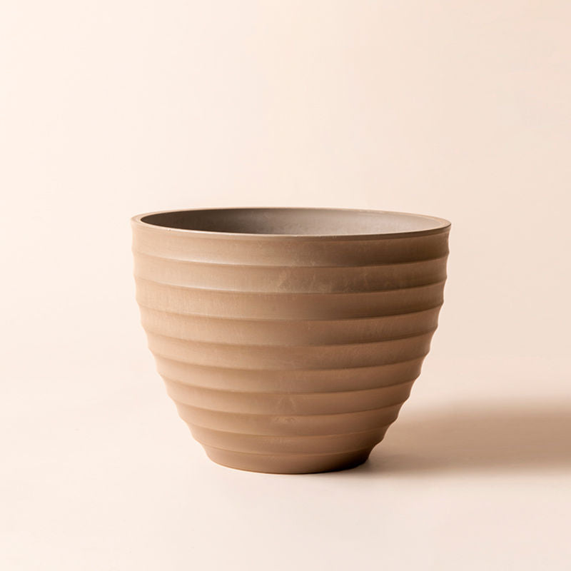 The full view of the greece taupe pot with smooth ridges tapering towards the bottom. The planter is made of plastic.