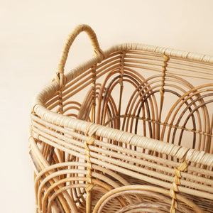 A close up of wicker basket, showing its arched handle and woven pattern.
