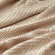 A close-up of the throw, showing its herringbone pattern in white and beige.