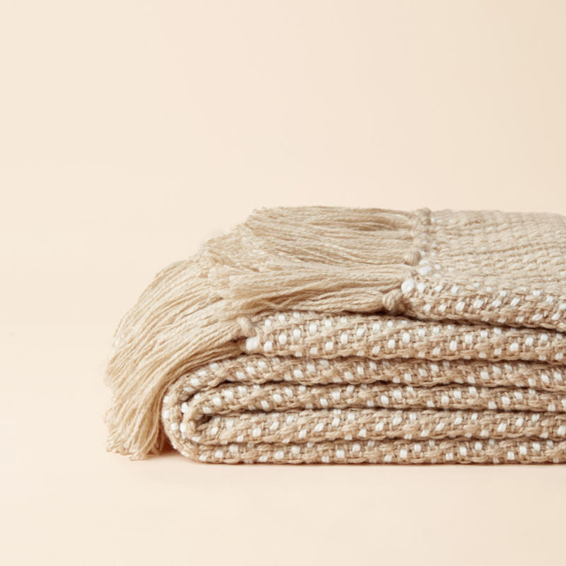 The brown throw with herringbone woven pattern design is folded.