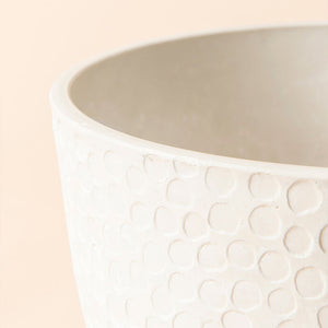 A close up of white plastic planter, showing a unique honeycomb pattern around its exterior.