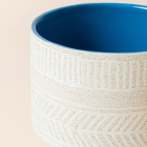 A close up of ivory white ceramic planter, showing the fully glazed galaxy blue interior.