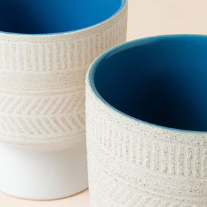 A close up of two ivory white pots, showing their consistent dimension in 6 inches.