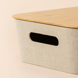 A close up of khaki bamboo storage basket, showing its fabric texture and a small opening on the side of the basket.