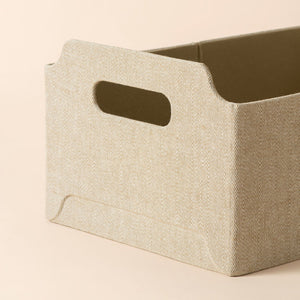 A close up of khaki rectangular basket, showing its tweed texture and small handle.