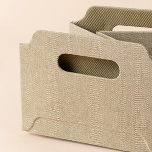 A close view of folded khaki rectangular basket, showing its soft collapsible material.