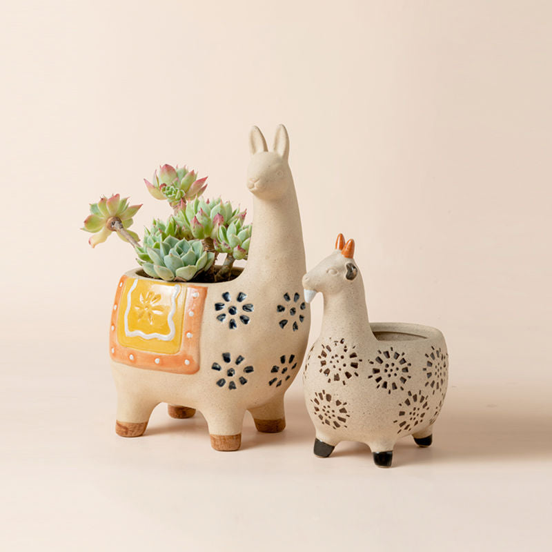 A set of small planters are in alpaca and goat shapes, one of which holds succulents plants.
