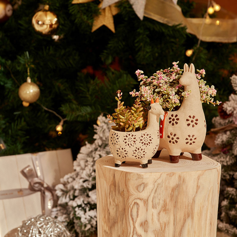 The set of two planters is displayed on a wooden stand, in front of a Christmas tree.