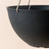 A close up of black hanging planter, showing its concrete texture and large dimension in 13.2 inches.